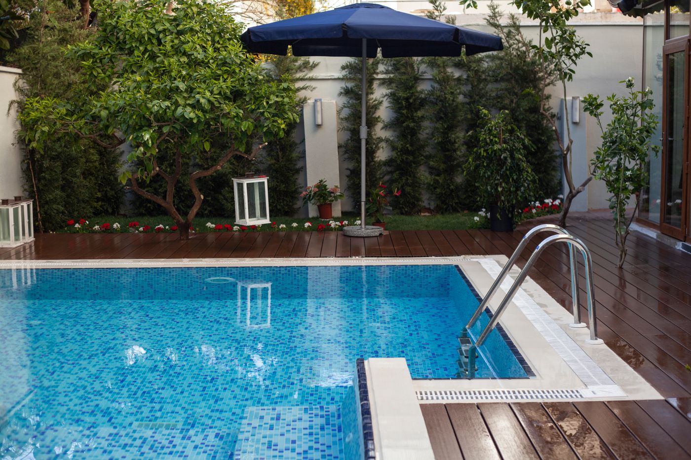 Clean residential swimming pool with blue mosaic waterline tile, coping and a stainless ladder — illustrative placeholder, not a verified CFPS project