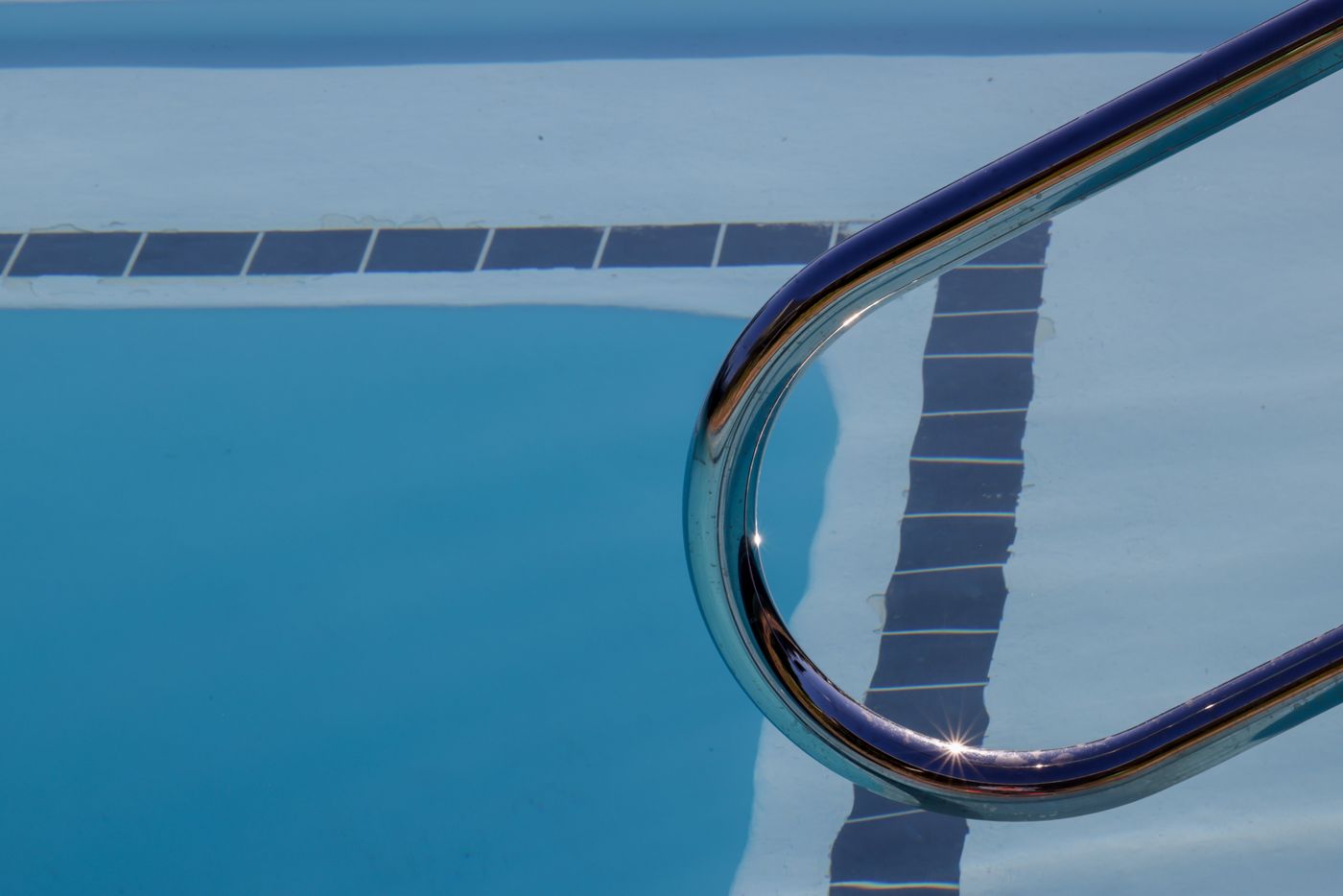 Smooth pool interior finish with a tile waterline band and stainless handrail — illustrative example of pool resurfacing, not a verified CFPS project