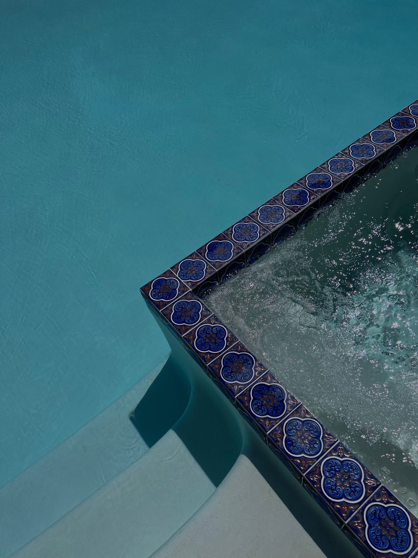 Decorative blue waterline tile detail along a pool/spa edge — illustrative example of waterline tile, not a verified CFPS project
